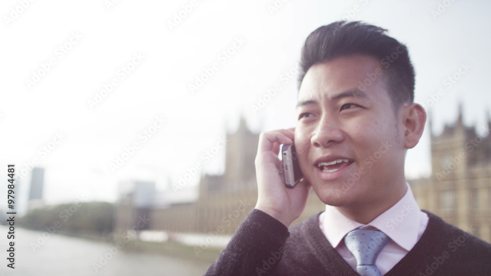Portrait of 2 cheerful Asian businessmen outdoors in city with mobile phone Portrait of 2 cheerful Asian businessmen outdoors in city with mobile phone