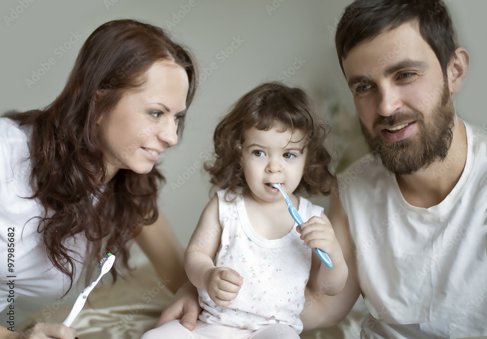 mother and fanher teaching little daughter clean teeth