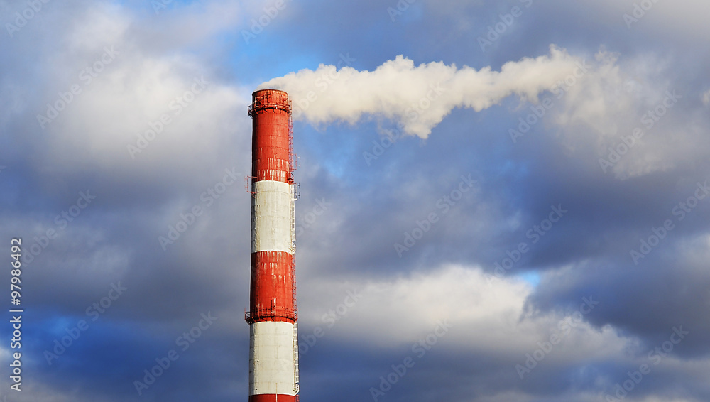 Pipe industrial chimney with smoke against the sky and clouds
