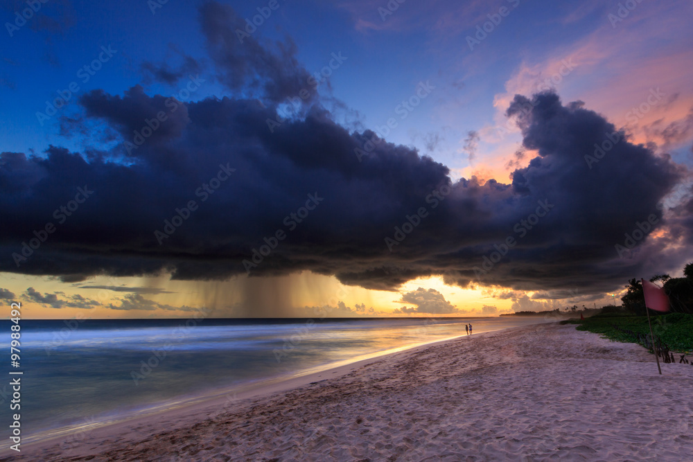 Sea  and beach with dark rain clouds at sunset