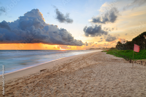 Sea and beach with dark rain clouds at sunset