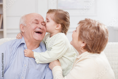 Cute small child is expressing love to grandparents photo