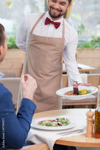 Attractive young waiter is working at restaurant