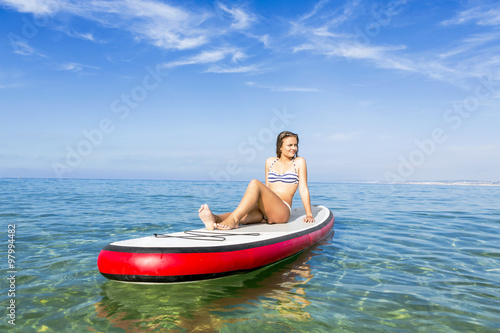 Woman sitting over a paddle surfboard © ikostudio