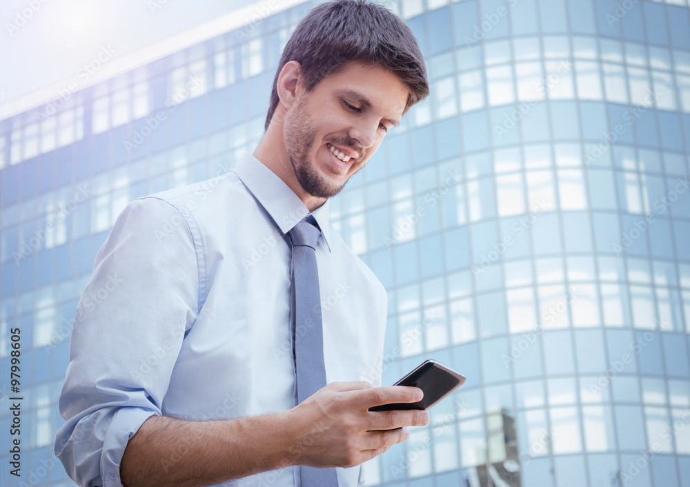 Young businessman using smartphone outside the office Young businessman using smartphone outside the office
