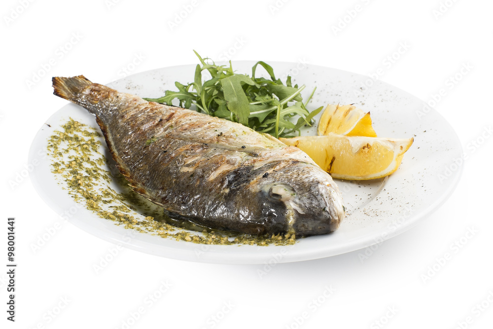 Fish fried on the grill with sauce, lemon and arugula Fish fried on the grill with sauce, lemon and arugula