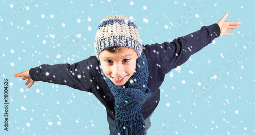 Winter - Excited little boy in warm clothes , opening his arms under falling snow - Top View
