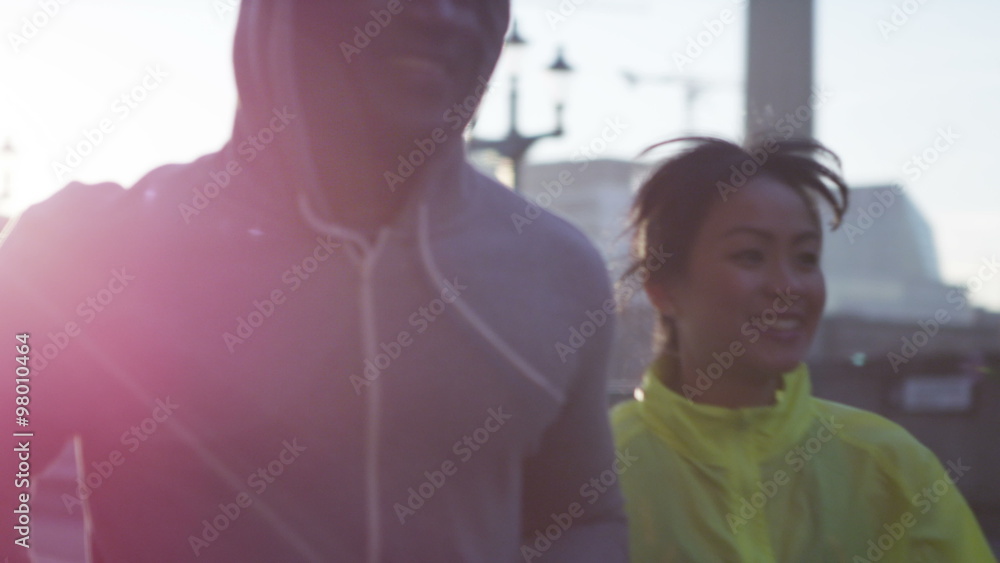 Athletic man and woman running together through urban environment Athletic man and woman running together through urban environment