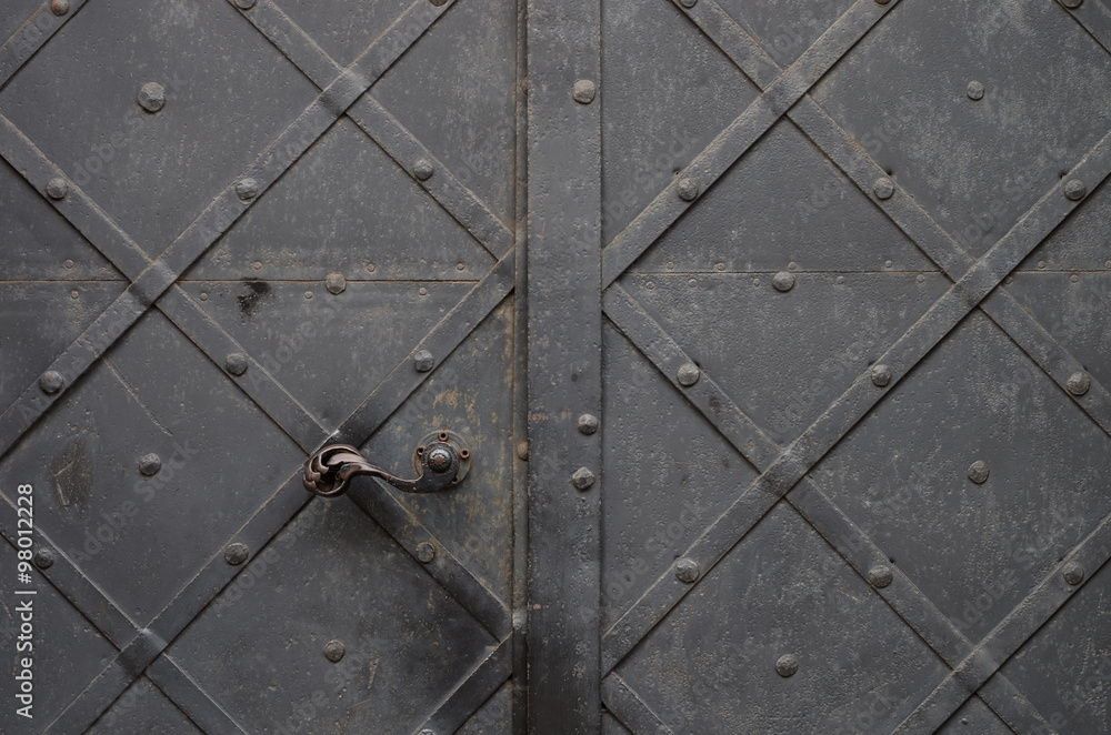 Ancient iron door with handle reinforced with steel belts and rivets
