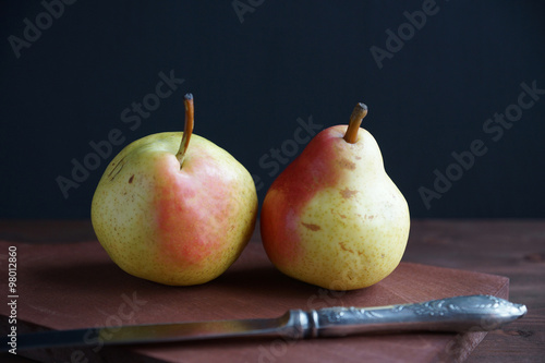 Two pears on a wooden board on a black background