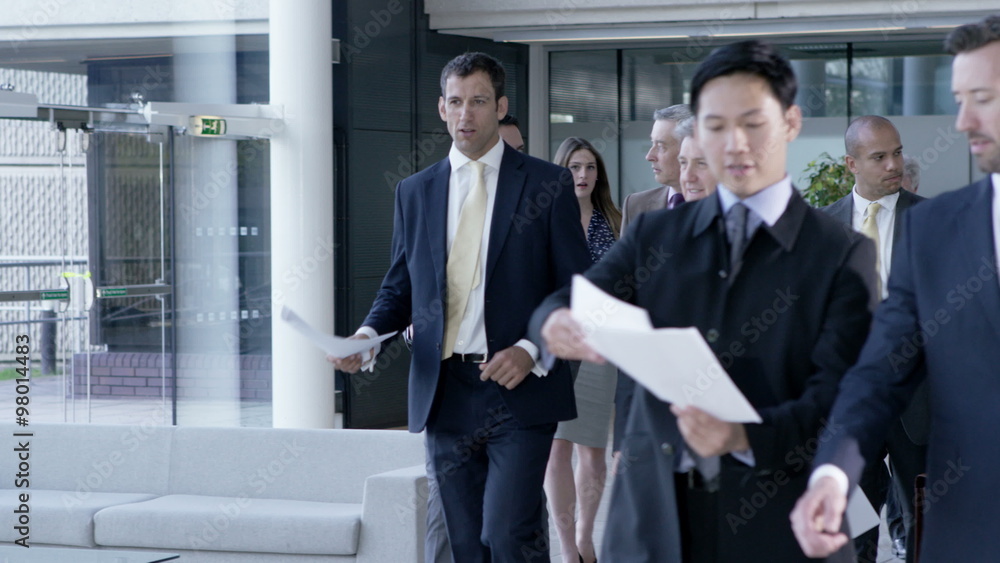 Large diverse business group talking as they walk through office building Large diverse business group talking as they walk through office building