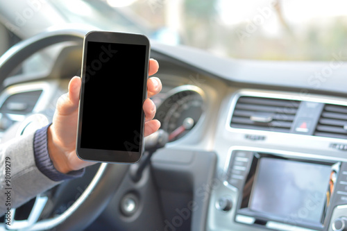 Smartphone hold by man inside a car while driving