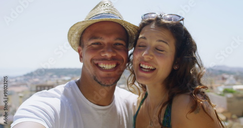 tractive happy couple relaxing together at the beach posing for a photograph with a camera phone