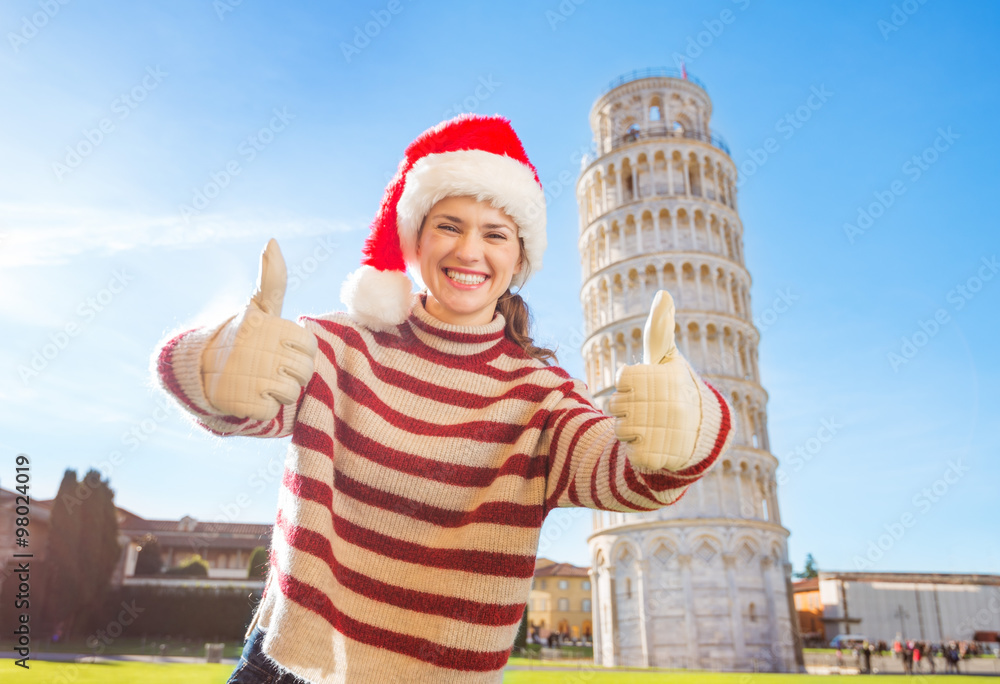 Obraz premium Woman in Santa hat showing thumbs up near Leaning Tour of Pisa