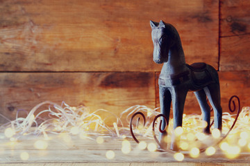 double exposure image of rocking horse and magic christmas lights on wooden table