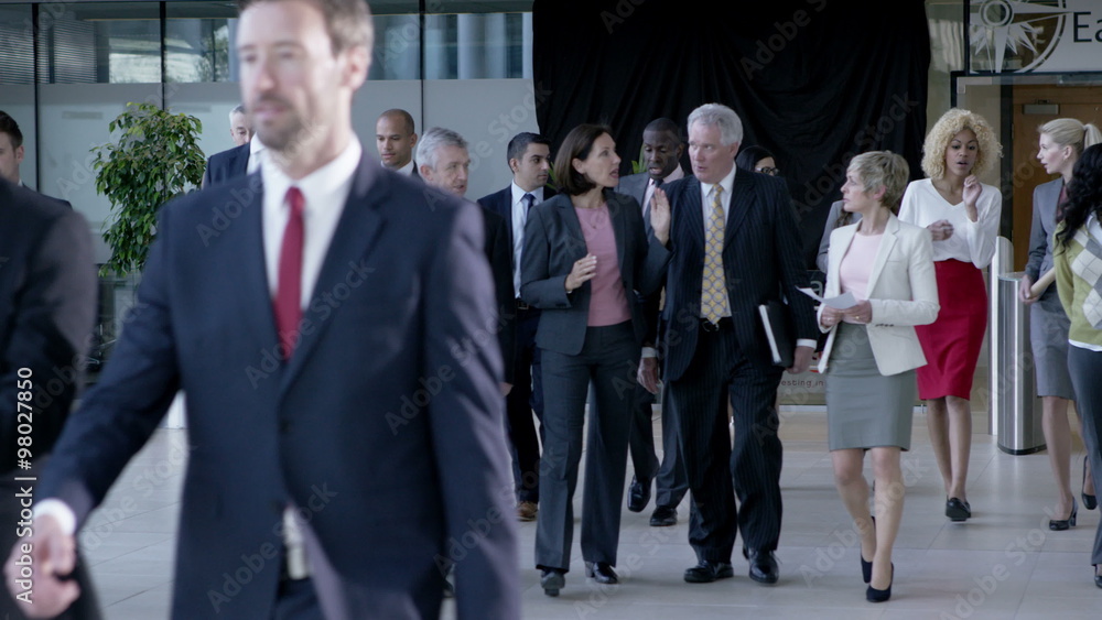Large diverse business group talking as they walk through office building Large diverse business group talking as they walk through office building