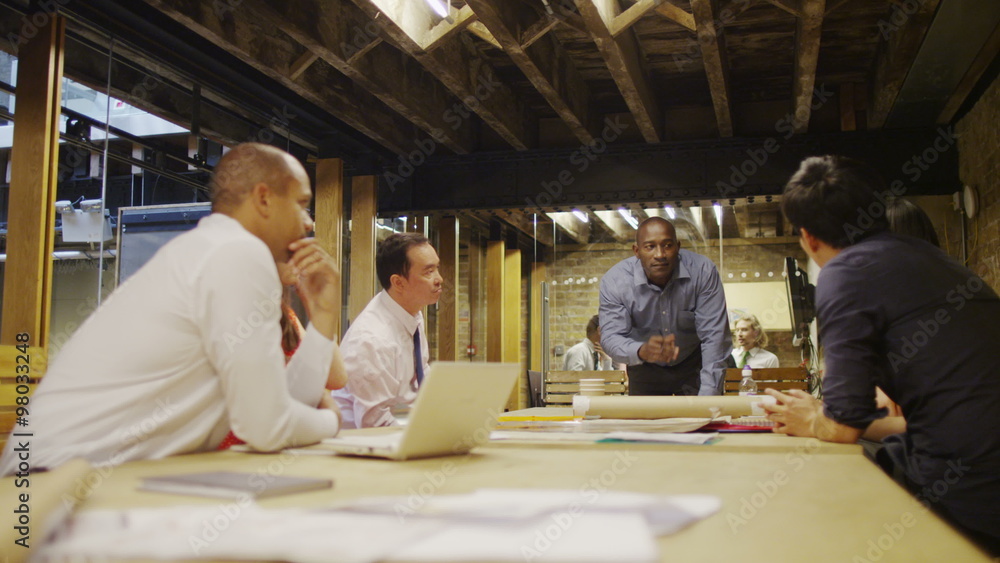 Company manager in a business meeting addresses his team of staff Company manager in a business meeting addresses his team of staff