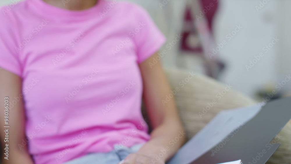 Gay female couple or flat mates in new home worried woman looks at paperwork while her partner paints a wall. Gay female couple or flat mates in new home worried woman looks at paperwork while her partner paints a wall.