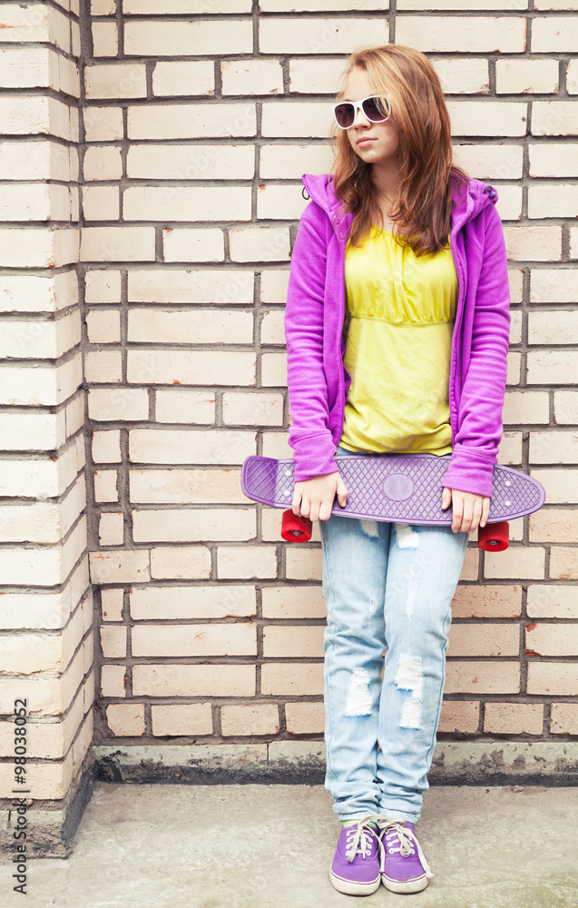 Girl in sunglasses and sporty clothes holds skateboard Girl in sunglasses and sporty clothes holds skateboard