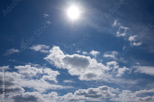 Beautiful celestial landscape with bright sun and white clouds on dark blue sky