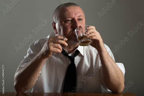Businessman drinking alcohol and smoking cigarette