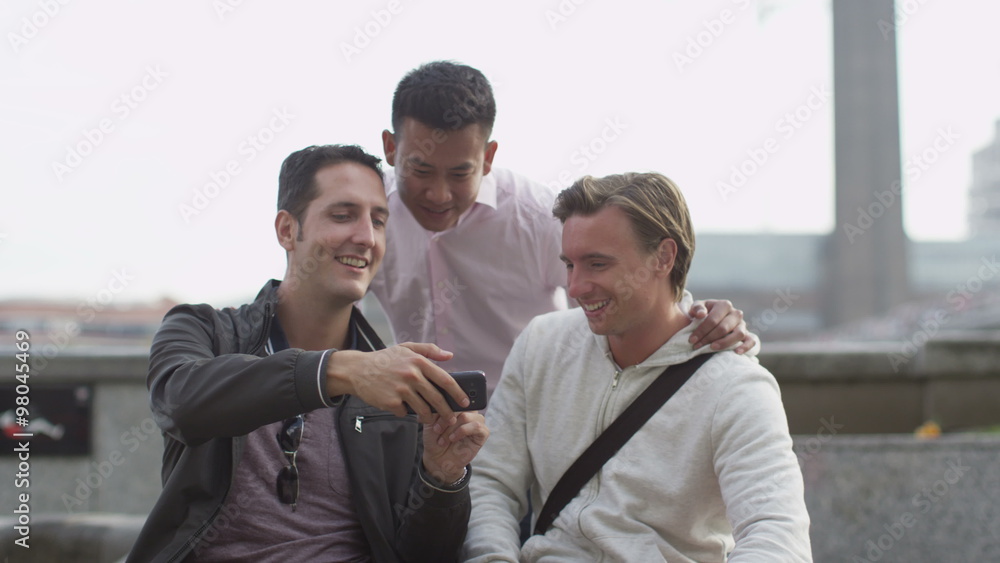 Group of casual male friends using mobile phones the city Group of casual male friends using mobile phones the city