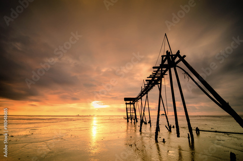 long exposure shot, old water pump tower with beautiful sunset sunrise with dramatic clouds at Jeram Beach, Malaysia