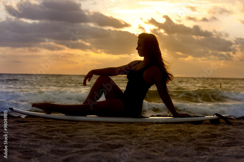 Silhouette of woman with surfboard on a beach © Aneese