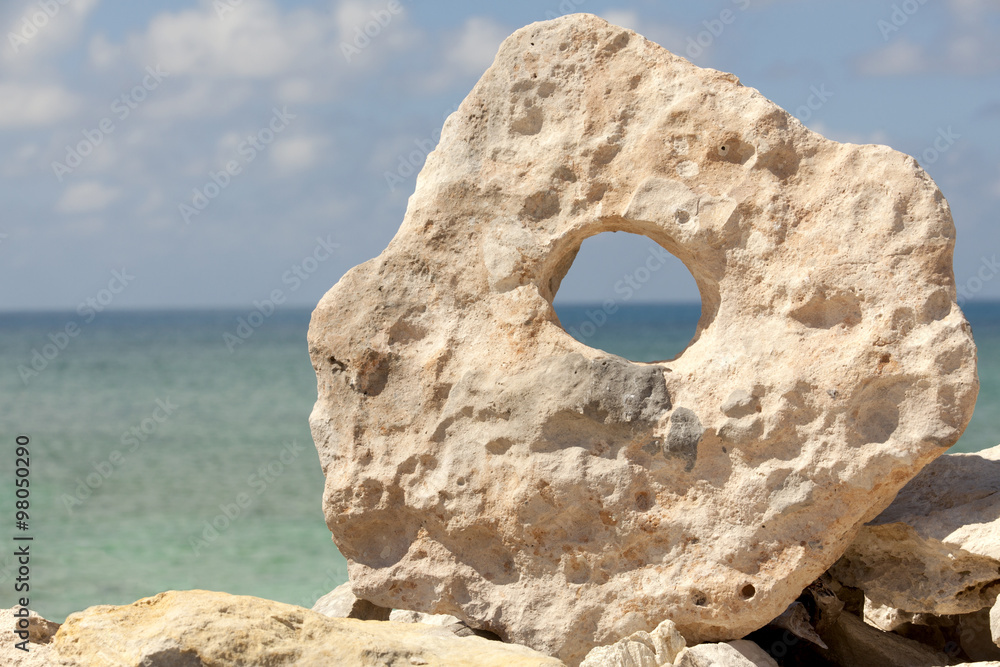 Rock with a hole with a tropical ocean in the background.

Off-center for copy space