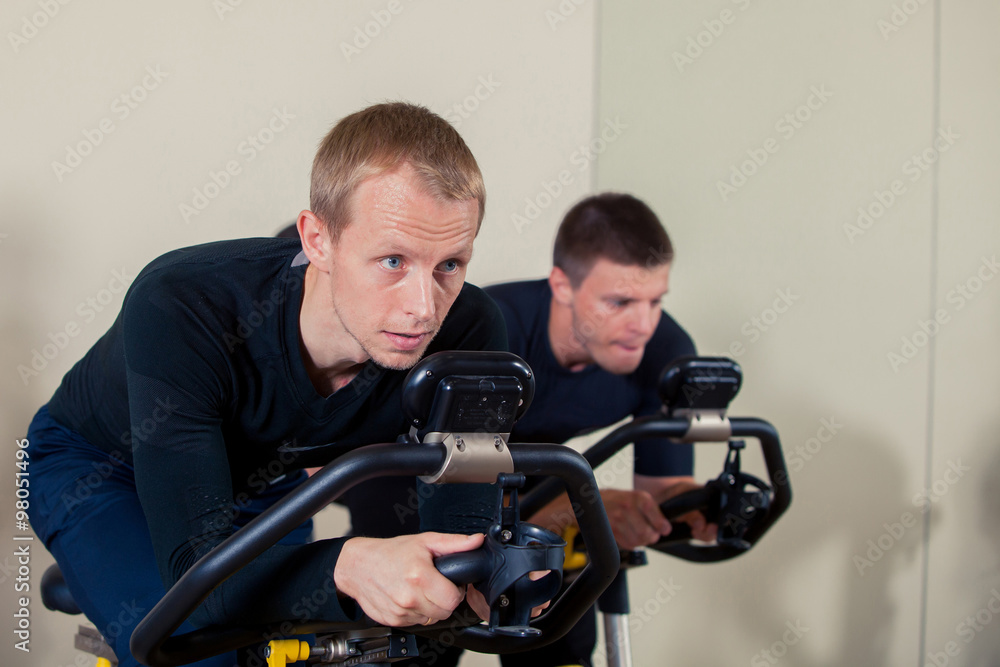 Group of gym people on machines, cycling In Class Group of gym people on machines, cycling In Class