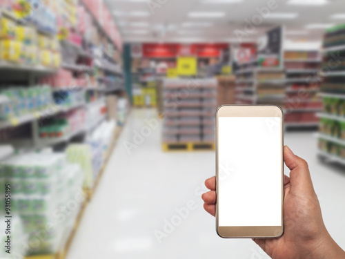 Hand with smartphone on blurred in department store