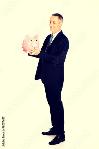 Full length side view businessman with piggybank