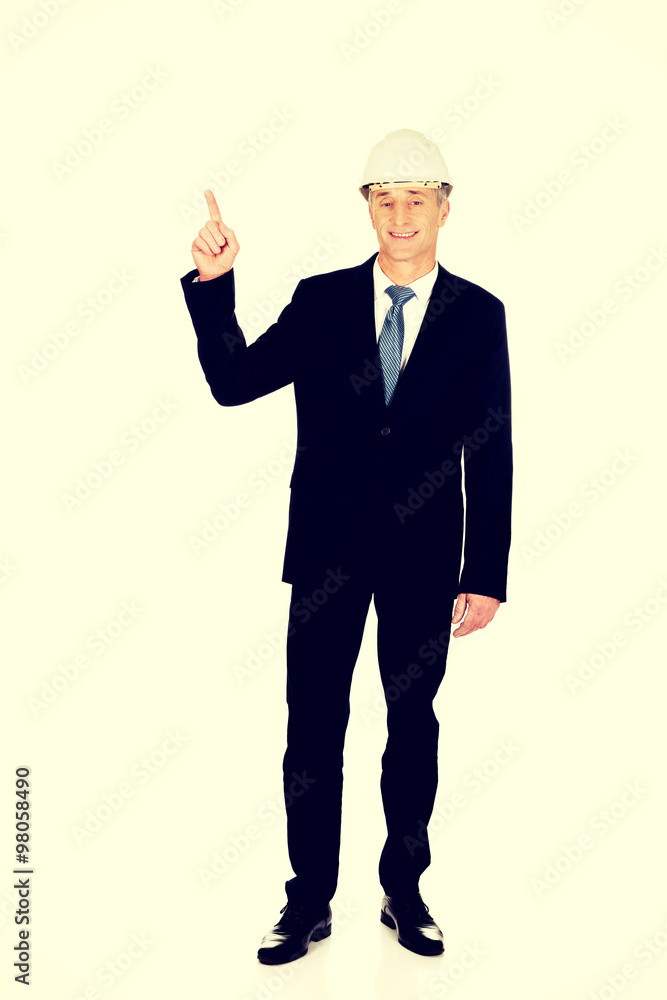 Smiling businessman with hard hat pointing up