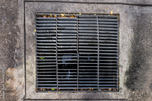 rectangular sewer with a rust and holes on cement ground