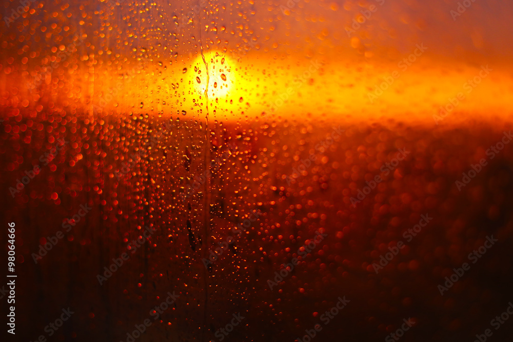 Water drops on a window glass after the rain. The sky with clouds and sun on background.