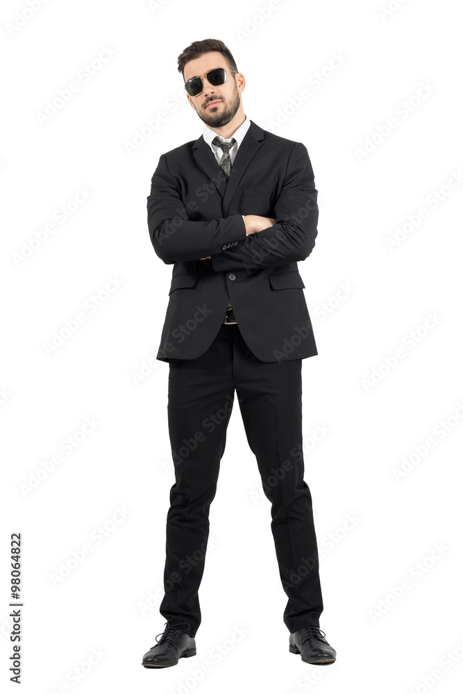 Secret agent or bodyguard with crossed arms looking at camera. Full body length portrait isolated over white studio background. Secret agent or bodyguard with crossed arms looking at camera. Full body length portrait isolated over white studio background.