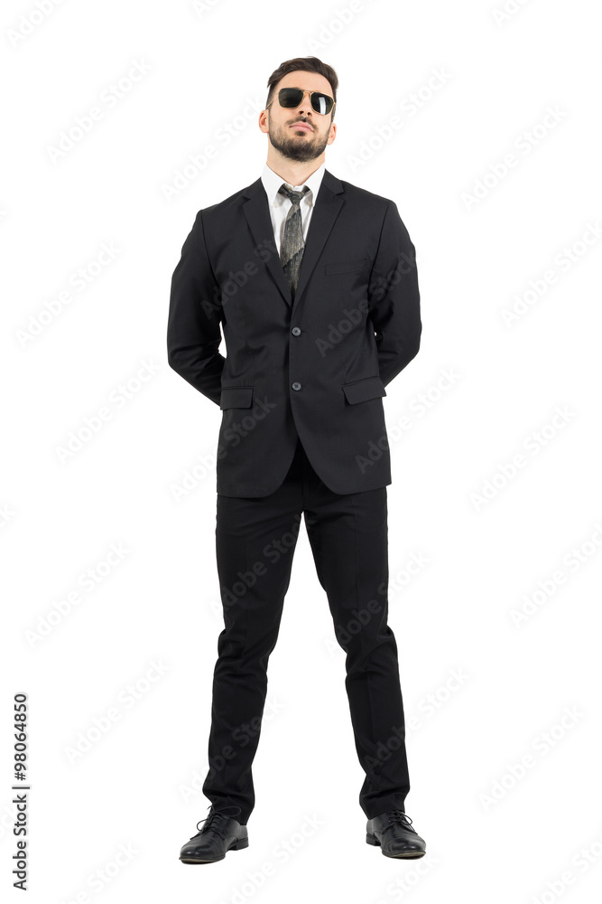 © sharplaninac - Secret agent or guard with hands behind back wearing sunglasses.Full body length portrait isolated over white studio background. © sharplaninac - Secret agent or guard with hands behind back wearing sunglasses.Full body length portrait isolated over white studio background.