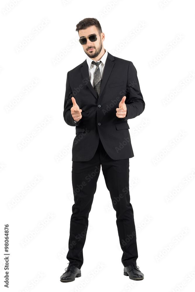 Secret agent with sunglasses aiming hand gun gesture at camera. Full body length portrait isolated over white studio background. Secret agent with sunglasses aiming hand gun gesture at camera. Full body length portrait isolated over white studio background.