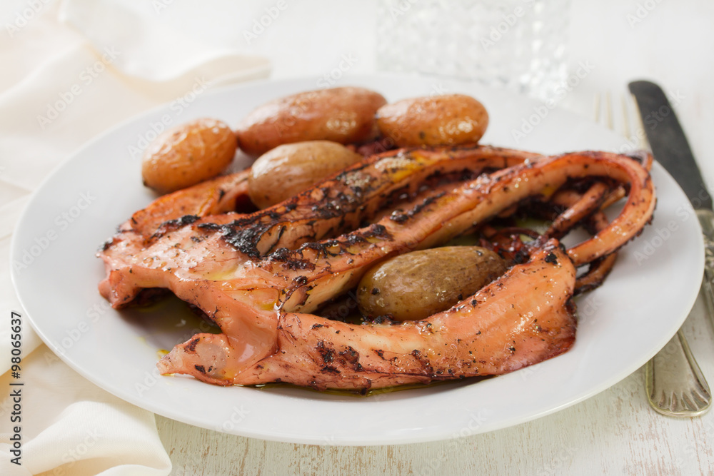 boiled octopus with potato on plate on white wooden background boiled octopus with potato on plate on white wooden background
