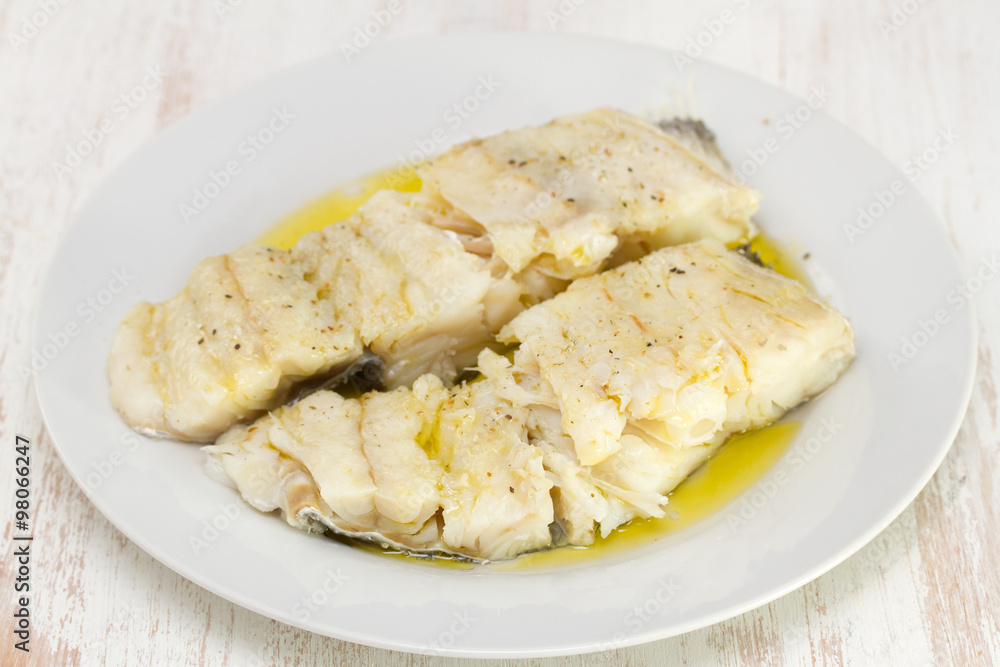 boiled cod fish with olive oil on white plate boiled cod fish with olive oil on white plate