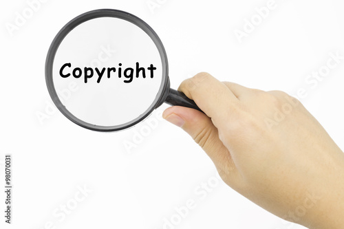 Hand showing Copyright word through magnifying glass
