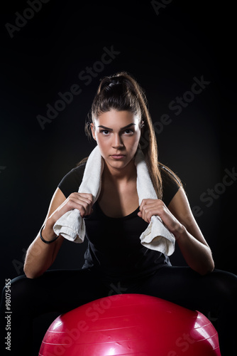 power fitness girl sitting on fitness ball isolated on black detail