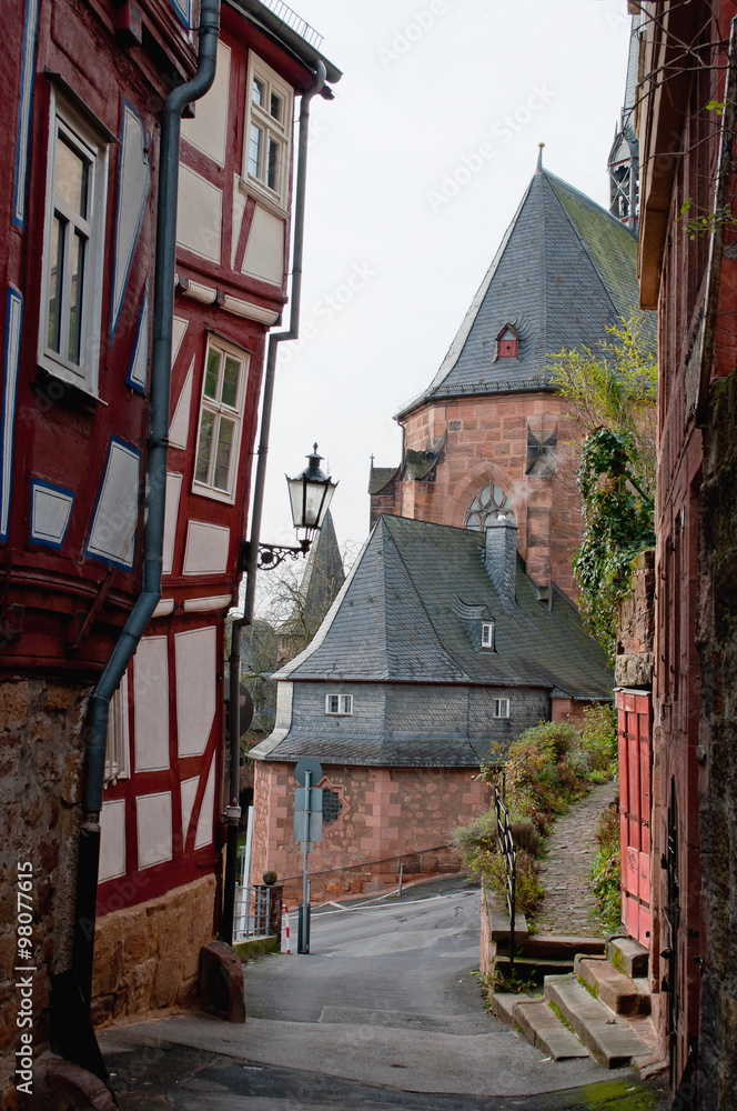 View on a church tower through a gap between half timbered houses in old town. Marburg, Germany