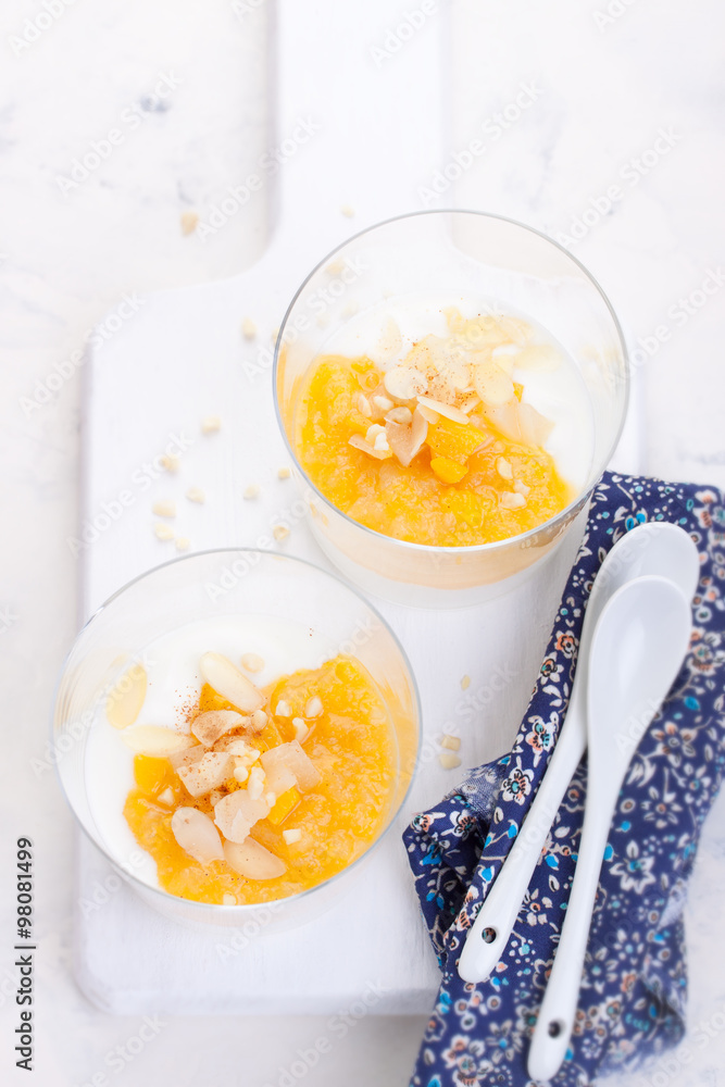 Sweet peach and pear compote with yogurt in a glass and jam on a white board. Sweet peach and pear compote with yogurt in a glass and jam on a white board.