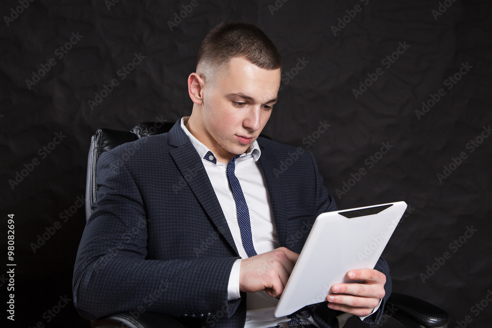 Successful young businessman smiling and looking at the screen of the tablet. Successful young businessman smiling and looking at the screen of the tablet.