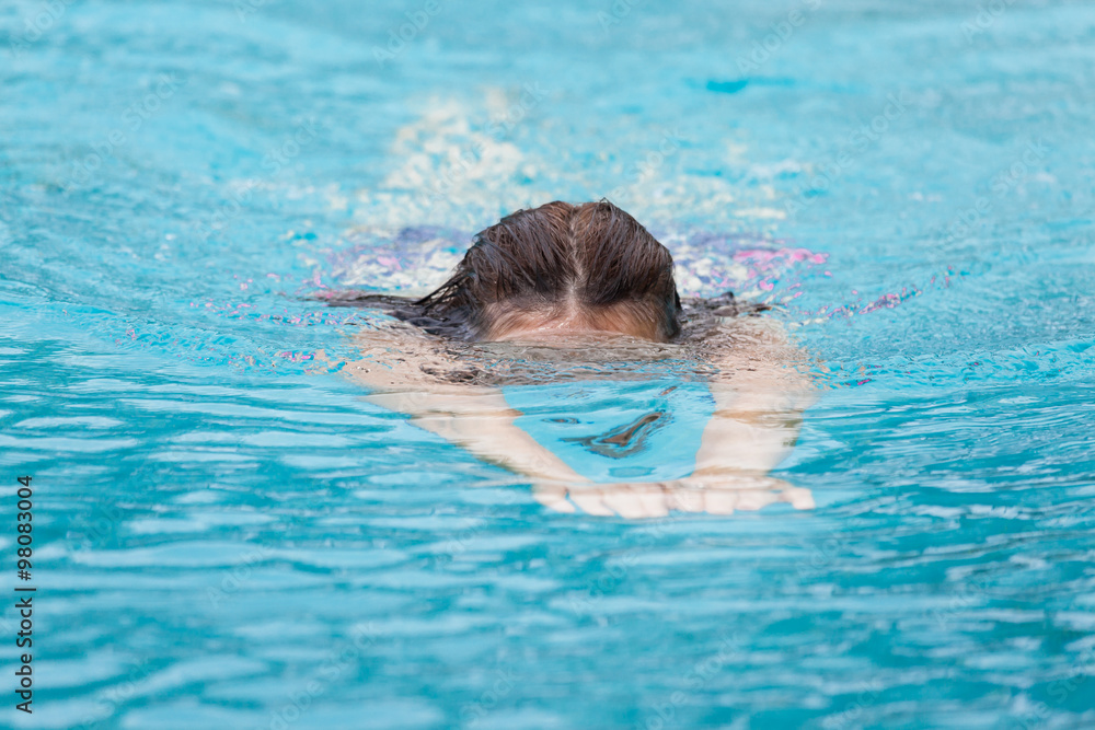 A woman while swimming, diving head just under the water