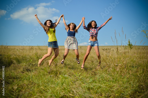 Teenage girls jumping on summer field