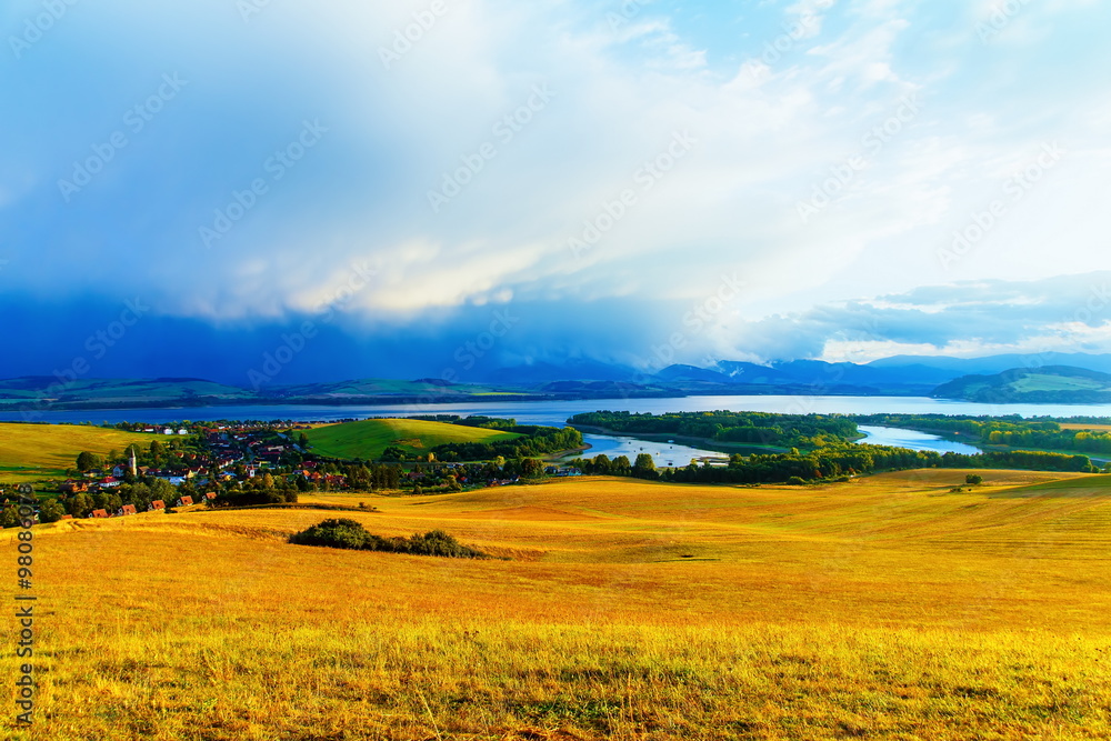 Fototapeta premium Beautiful landscape, green and yellow meadow and lake with village. Slovakia, Central Europe.