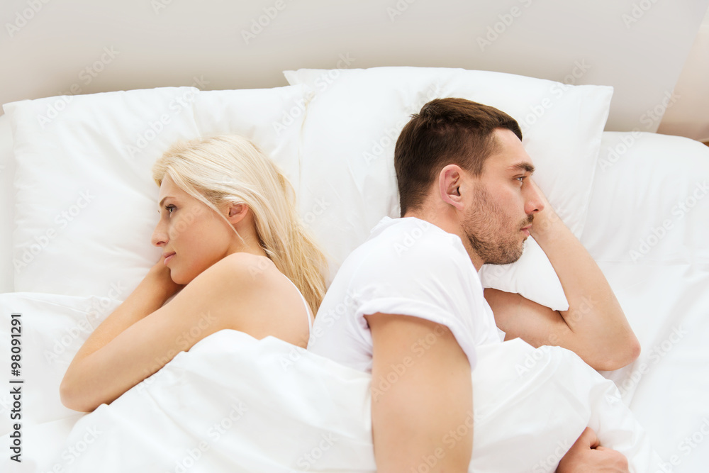 unhappy couple lying in bed at home unhappy couple lying in bed at home