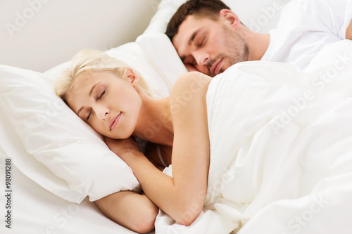 happy couple sleeping in bed at home